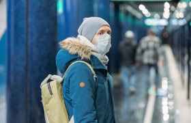 a male waiting the subway is wearing a face mask
