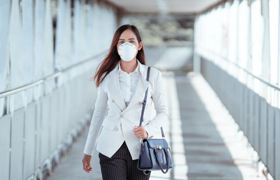 a female wearing an N95 mask is walking on the street