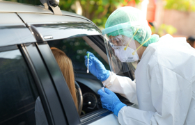 a female wearing both a N95 mask and face shield are having a testing for people in the car